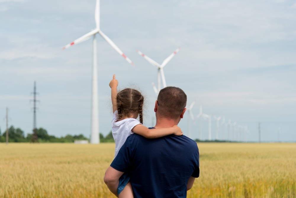 Man met kind kijken naar een windpark en graanveld