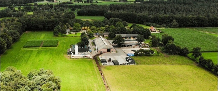 Boerderij van bovenaf gezien met velden en bomen er omheen